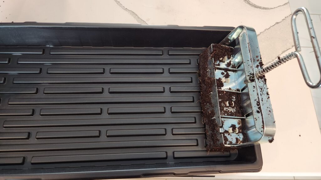Getting ready to empty soil blocker into new tray.