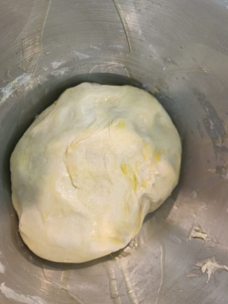 Dough ball covered in olive oil in large bowl.