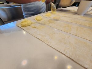 Dolloping triopita mixture onto the bottom of the sheet