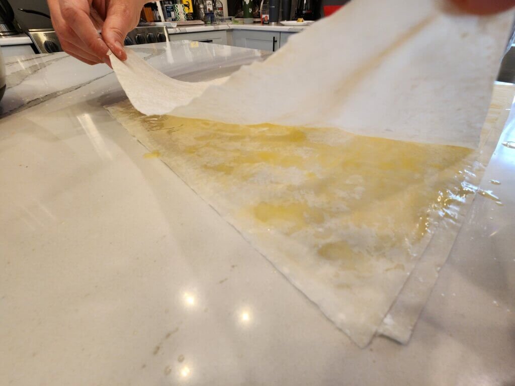 Draping Phyllo sheet over the previous buttered layers