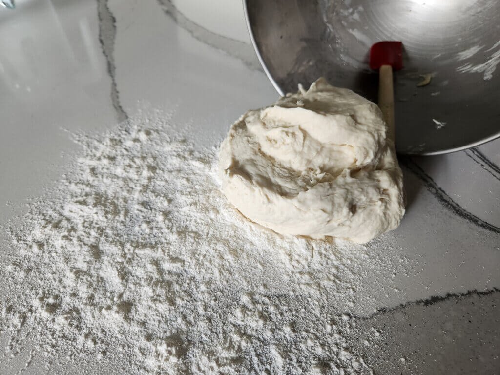 Fresh bread dough on counter with some flour
