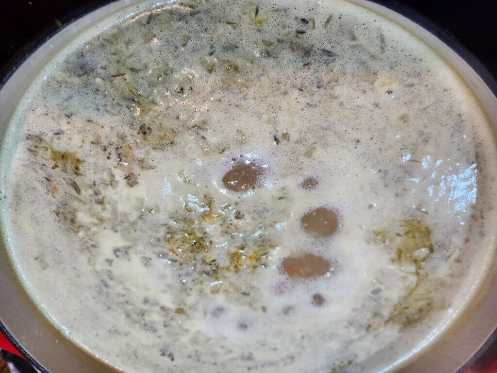 Hearty leftover turkey soup with orzo and barley simmering in a Dutch oven – cozy homemade comfort food recipe.