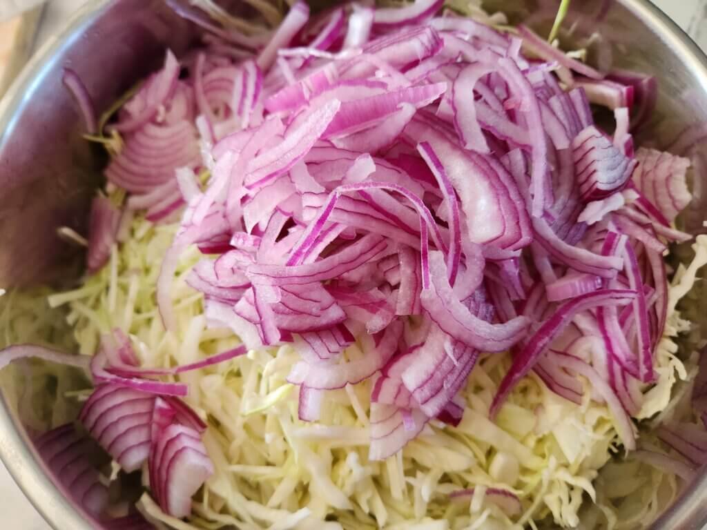 Red onion added to homemade creamy coleslaw