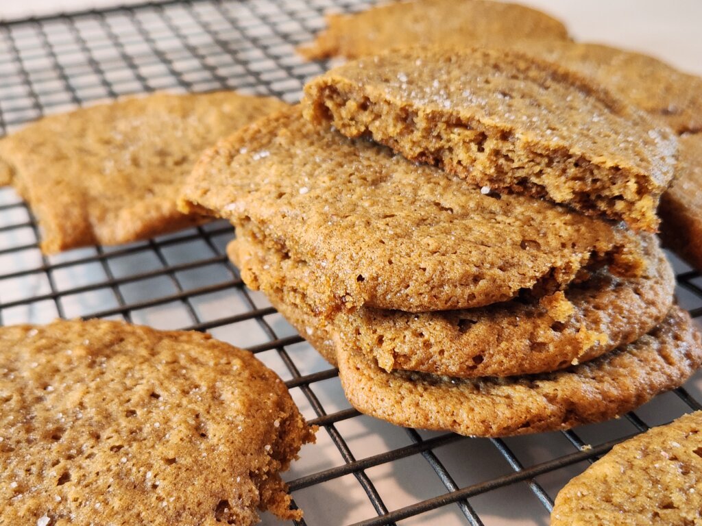 Homemade pumpkin spice cookies stacked on a cooling rack with one broken open to show the soft center.