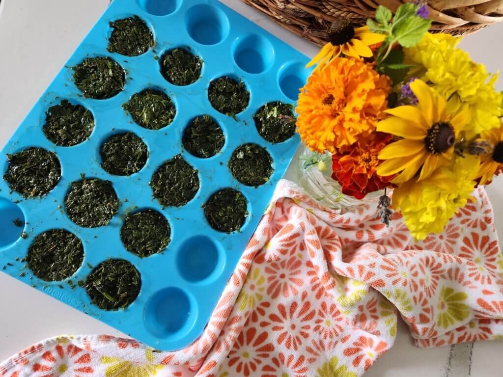 Chopped fresh basil and olive oil portioned in a silicone tray for freezing